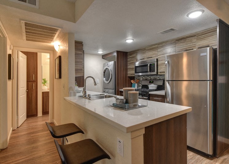 Kitchen with In Unit Washer Dryer and View of Hallway with Hardwood Inspired Floor, Refrigerator and Microwave